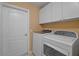 Well-lit laundry room features white cabinets, a washer and dryer, and a door to another room at 397 Anderson Dr, Tavares, FL 32778