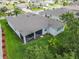 Aerial view of backyard and lawn with screen enclosed patio featuring chairs and a table, and lush manicured grass at 4581 Shenandoah River Trl, Leesburg, FL 34748