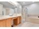Bathroom featuring a double vanity, a glass-enclosed shower, and a separate soaking tub with tile flooring at 4716 Block Island Ln, Clermont, FL 34714