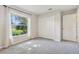 Bright bedroom with a closet, a window overlooking the front yard, and neutral carpeting at 508 Woodview Dr, Tavares, FL 32778