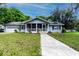 Charming single-story home with a welcoming screened front porch, well-manicured lawn, and a long concrete walkway at 513 Barwick St, Wildwood, FL 34785