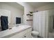 The bathroom has a single sink vanity, decorative shelves, and a shower with a white floral curtain at 5333 Loblolly Ln, Wildwood, FL 34785