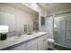 Bright bathroom with a double sink vanity, large mirror, and glass-enclosed shower with decorative curtain at 5333 Loblolly Ln, Wildwood, FL 34785