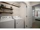 This laundry room features modern appliances, wooden shelves, and convenient access to the bedroom at 5333 Loblolly Ln, Wildwood, FL 34785
