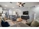 Open-concept living room with ceiling fan, neutral tones, a modern entertainment center, and a view into the kitchen at 5333 Loblolly Ln, Wildwood, FL 34785