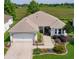 Aerial view of single-story home featuring lush landscaping, well-manicured lawn, pond view, and a two-car garage at 541 Carrera Dr, The Villages, FL 32159