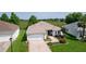 Aerial view of the home with lush landscaping, an extended driveway, and a view of the surrounding greenery at 541 Carrera Dr, The Villages, FL 32159