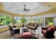 Bright sunroom featuring ample seating, a ceiling fan, and large windows with views of the lush backyard at 541 Carrera Dr, The Villages, FL 32159