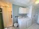 A clean laundry room features a washer, dryer, storage cabinets, and access to the shower at 603 W Seminole Ave, Eustis, FL 32726