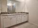 Bathroom features a dual sink vanity with granite countertop, a large mirror, and a walk-in shower at 6203 Sw 93Rd Loop, Ocala, FL 34476