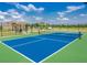 Outdoor pickleball court featuring a blue surface, green surroundings, and shaded seating area at 6203 Sw 93Rd Loop, Ocala, FL 34476