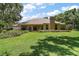A beautiful backyard showcasing a spacious lawn and mature landscaping creating a private outdoor space at 621 High Point Dr, Mount Dora, FL 32757