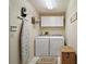 This bright laundry room includes side-by-side washer and dryer with storage and an ironing board at 621 High Point Dr, Mount Dora, FL 32757