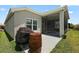 Back patio with a grill and barrels, plus a screened-in porch area with a ceiling fan and table at 6243 Danielson Loop, The Villages, FL 32163