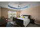 Bedroom with a trey ceiling, comfortable bed and a neutral decor with ample natural light at 6243 Danielson Loop, The Villages, FL 32163