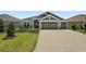 Charming home featuring a three-car garage, well-manicured lawn, and inviting front entrance at 6243 Danielson Loop, The Villages, FL 32163