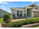 Inviting front porch featuring rocking chairs, bench seating, and lush landscaping at 6243 Danielson Loop, The Villages, FL 32163