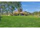 A charming home boasts a lush lawn, mature palm trees, and an inviting outdoor living space at 7629 Lake Angelina Dr, Mount Dora, FL 32757