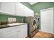 Modern laundry room featuring a sink, stainless steel washer and dryer, and green walls at 7629 Lake Angelina Dr, Mount Dora, FL 32757