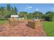Inviting brick patio with comfortable wicker seating, lush landscaping, and a peaceful backyard setting at 7629 Lake Angelina Dr, Mount Dora, FL 32757