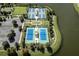Overhead shot of tennis and playing courts with lush landscaping and a view of the lake at 7873 Crosswinds Way, Mount Dora, FL 32757