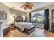 Comfortable bedroom with a ceiling fan, plush bed, and a view of the outdoors through the large window at 7873 Crosswinds Way, Mount Dora, FL 32757