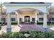 Up close Clubhouse view with manicured shrubs, flowers, and benches at the covered entrance at 7873 Crosswinds Way, Mount Dora, FL 32757