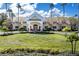 Beautiful clubhouse featuring a covered entrance, mature trees, and well manicured landscaping at 7873 Crosswinds Way, Mount Dora, FL 32757