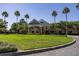 Beautiful community clubhouse featuring a covered entrance, lush landscaping, and palm tree accents at 7873 Crosswinds Way, Mount Dora, FL 32757