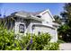 Charming home exterior featuring a two-car garage, gray paint, decorative window, and lush landscaping at 7873 Crosswinds Way, Mount Dora, FL 32757