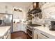 Modern kitchen with stainless steel appliances, white cabinets, quartz countertops, and a stylish range hood at 7873 Crosswinds Way, Mount Dora, FL 32757