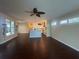 Spacious living room with dark wood floors, fan, and view into the modern kitchen and backyard at 7873 Crosswinds Way, Mount Dora, FL 32757