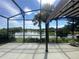 Outdoor patio with screened in area overlooking tranquil lake and palm trees at 7873 Crosswinds Way, Mount Dora, FL 32757