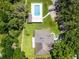 Aerial view of a private backyard oasis featuring a sparkling pool, lush lawn, and mature trees creating a serene retreat at 8527 Firestone Cir, Clermont, FL 34711
