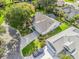 Aerial view of well-manicured home featuring mature trees, landscaped yard, paved driveway, and blue car at 8980 Se 178Th Muirfield Pl, The Villages, FL 32162