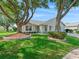 Charming single story home featuring mature trees, landscaped yard, paved pathway, and attached two car garage at 8980 Se 178Th Muirfield Pl, The Villages, FL 32162
