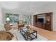 Bright living room featuring wood floors, a ceiling fan, TV, and a sliding glass door leading to the patio at 8980 Se 178Th Muirfield Pl, The Villages, FL 32162