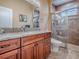 Bathroom with wood cabinetry, granite counters, and glass-enclosed shower at 10994 Se 168Th Loop, Summerfield, FL 34491