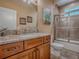 Bathroom with brown wooden cabinet, light granite top, and tiled shower with glass door at 10994 Se 168Th Loop, Summerfield, FL 34491