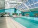 Bright indoor pool with a skylight, offering a refreshing and relaxing experience in a climate-controlled environment at 10994 Se 168Th Loop, Summerfield, FL 34491