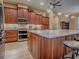 Open kitchen with granite countertops, island with bar seating and premium stainless appliances at 10994 Se 168Th Loop, Summerfield, FL 34491