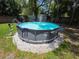 Backyard featuring a round above ground pool surrounded by stone and a green lawn at 1104 Flamingo Dr, Leesburg, FL 34748