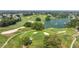 Scenic aerial view of a golf course with a lake, sand traps, and beautifully manicured greens at 1146 W Boone Ct, Lady Lake, FL 32159