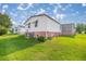 Spacious backyard with green grass and the home's exterior, including brick foundation detail at 1146 W Boone Ct, Lady Lake, FL 32159