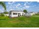 Well-maintained front yard with lush green grass, landscaping, and a charming white home at 1146 W Boone Ct, Lady Lake, FL 32159