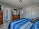Bright bedroom featuring a comfortable blue striped bed and a wooden dresser with sliding closet doors at 1202 Fernando Ln, The Villages, FL 32159