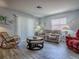Comfortable living room with a neutral sofa, red arm chair, and a glass coffee table for relaxing at 1202 Fernando Ln, The Villages, FL 32159
