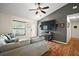 Bright living room featuring hardwood floors and a gray accent wall, with large TV and modern ceiling fan at 1204 Monterey Dr, Eustis, FL 32726