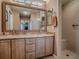 Bathroom featuring double sinks with granite countertops, a large mirror, and walk-in shower at 1206 Thompson Ave, The Villages, FL 32162