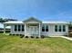 Charming single story home with a metal roof, a manicured lawn, and a quaint front porch at 12077 Lakeshore Way, Oxford, FL 34484